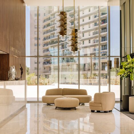 Modern lobby with a beige and wood interior, featuring large floor-to-ceiling windows with white frames that let in natural light - Reynaers